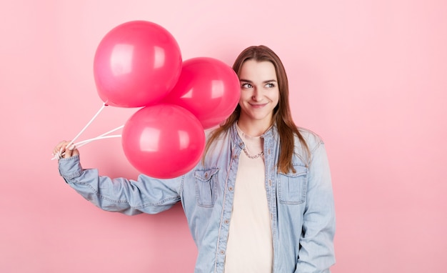 Jeune femme caucasienne tenant des ballons avec une expression heureuse et célébrant la Saint-Valentin