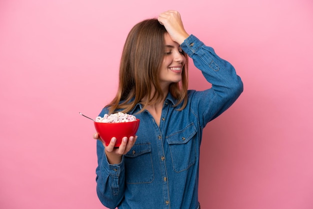 Une jeune femme caucasienne tenant un bol de céréales isolé sur fond rose a réalisé quelque chose et a l'intention de trouver la solution