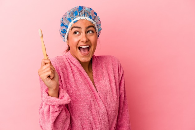 Jeune femme caucasienne tenant une brosse à dents isolée sur mur rose