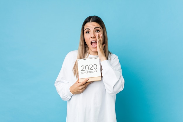 Jeune femme caucasienne tenant un calendrier 2020 criant excité à l'avant.