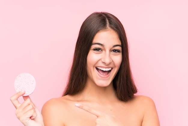 Jeune femme caucasienne tenant un disque facial isolé souriant pointant joyeusement avec l'index loin.