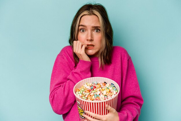 Jeune femme caucasienne tenant du pop-corn isolé sur fond bleu