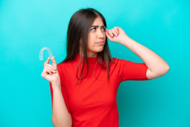 Jeune femme caucasienne tenant un envisageant isolé sur fond bleu ayant des doutes et avec une expression de visage confuse