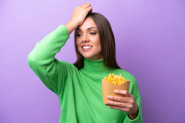 Une jeune femme caucasienne tenant des frites frites sur fond violet a réalisé quelque chose et a l'intention de trouver la solution