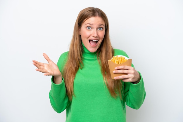 Jeune femme caucasienne tenant des frites frites isolées sur fond blanc avec une expression faciale choquée