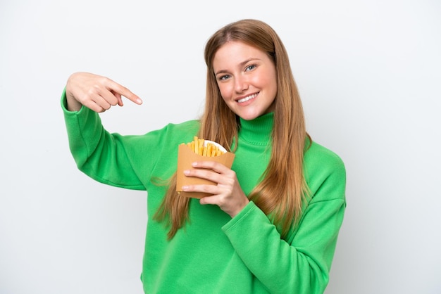 Jeune femme caucasienne tenant des frites frites isolées sur fond blanc et le pointant