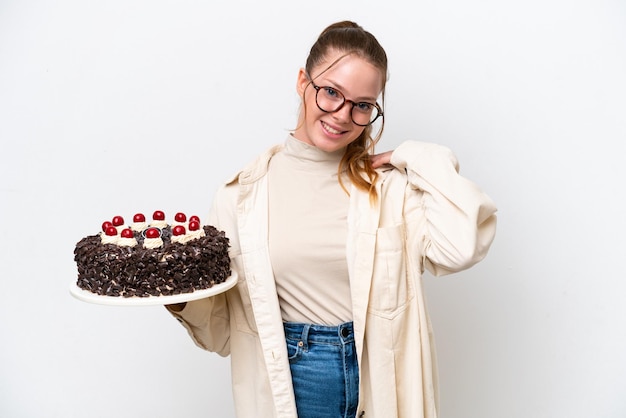 Jeune femme caucasienne tenant un gâteau d'anniversaire isolé sur fond blanc en riant