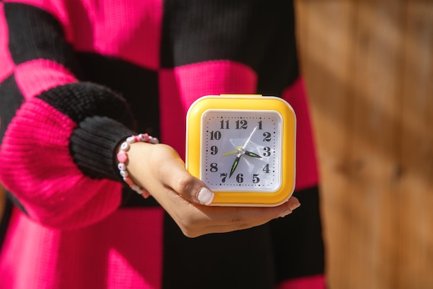 Une jeune femme caucasienne tenant une horloge