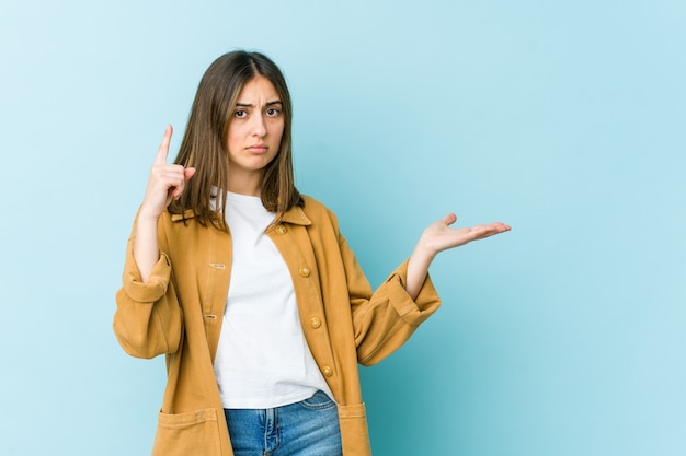 Jeune femme caucasienne tenant et montrant un produit sous la main.