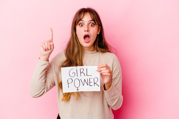 Jeune femme caucasienne tenant une pancarte de puissance de fille isolée sur fond rose ayant une idée, concept d'inspiration.