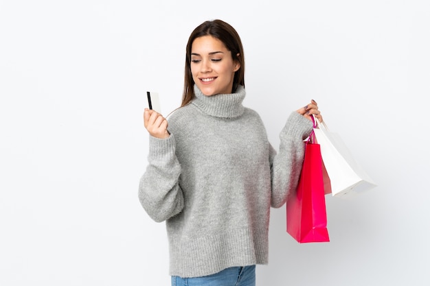 Jeune femme caucasienne tenant des sacs à provisions et une carte de crédit