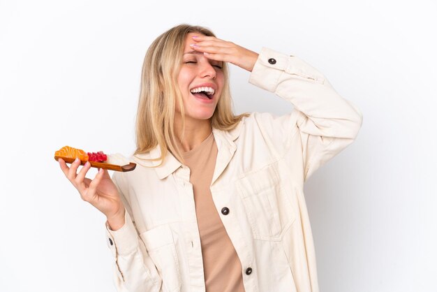 Jeune femme caucasienne tenant sashimi isolé sur fond blanc souriant beaucoup