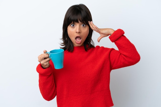 Jeune femme caucasienne tenant une tasse de café isolée sur fond blanc avec une expression de surprise