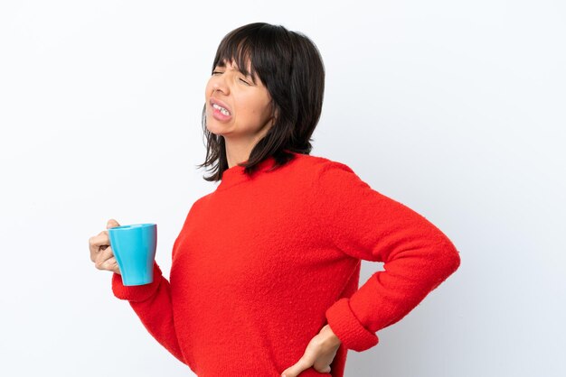 Jeune femme caucasienne tenant une tasse de café isolée sur fond blanc souffrant de maux de dos pour avoir fait un effort