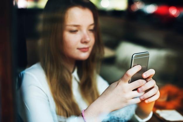 Jeune femme caucasienne utilise un téléphone mobile