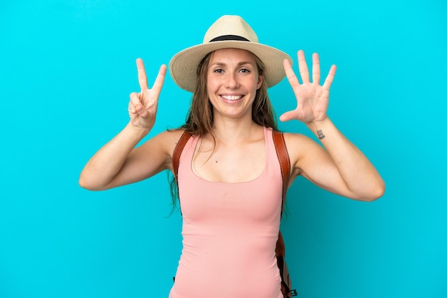 Jeune femme caucasienne en vacances d'été isolée sur fond bleu comptant sept avec les doigts