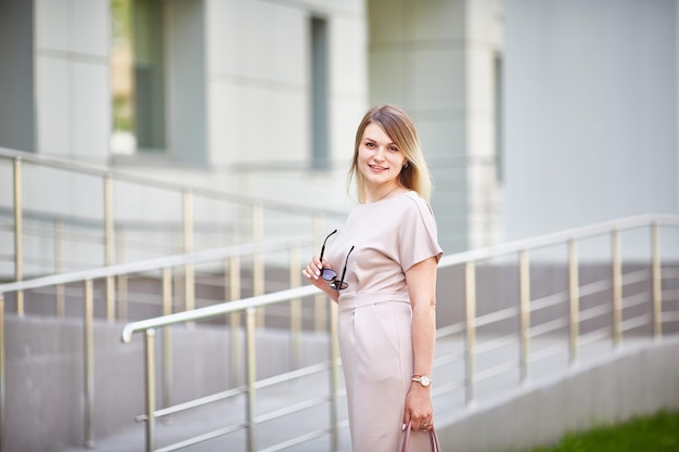 Une jeune femme caucasienne vêtue d'une belle robe dans la rue regarde la caméra et sourit