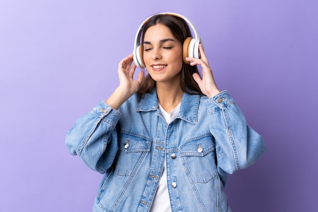 Jeune femme caucasienne sur violet écoute de la musique et du chant