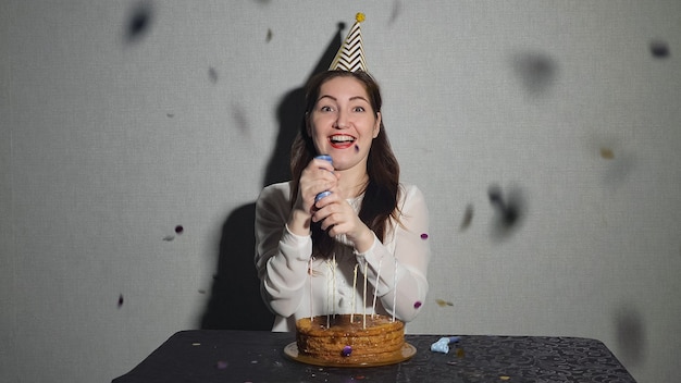 Jeune femme célèbre des vacances, il est assis seul à une table avec un gâteau et des bougies.