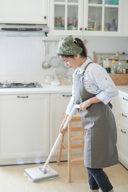 Une Jeune Femme De Chambre Nettoie La Maison Avec Une Vadrouille Il Y A Une Toile De Fond De Cuisine