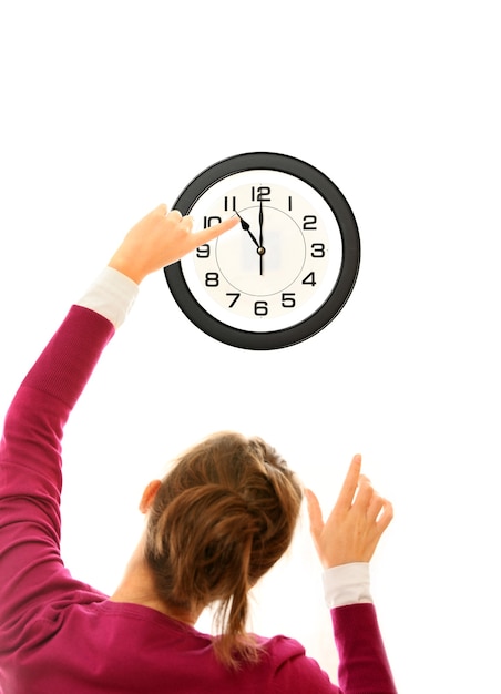 Jeune femme changeant l'heure sur une grosse horloge