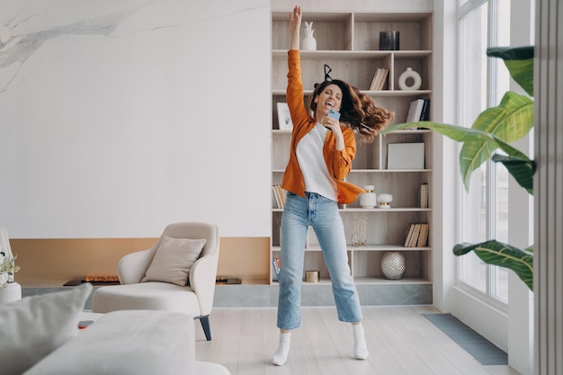 Jeune femme chante, danse et saute Fille s'amusant fou et criant à la maison