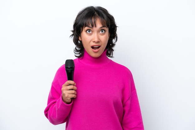 Jeune femme chanteuse argentine isolée sur fond blanc en levant et avec une expression surprise