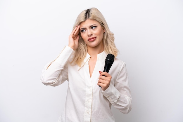 Jeune femme chanteuse ramasser un microphone isolé sur fond blanc avec des maux de tête