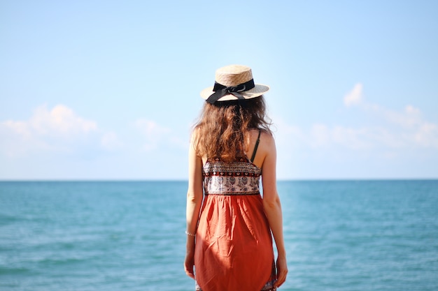 Jeune femme avec un chapeau au bord de la mer