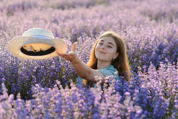 Une jeune femme avec un chapeau dans un champ de lavande