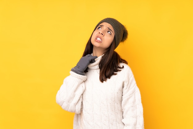 Jeune femme avec chapeau d'hiver sur fond jaune isolé avec une expression fatiguée et malade