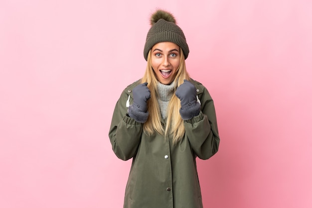 Jeune femme avec chapeau d'hiver posant isolé contre le mur blanc