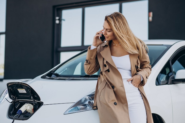 Jeune femme chargeant sa voiture électrique avec un pistolet de charge