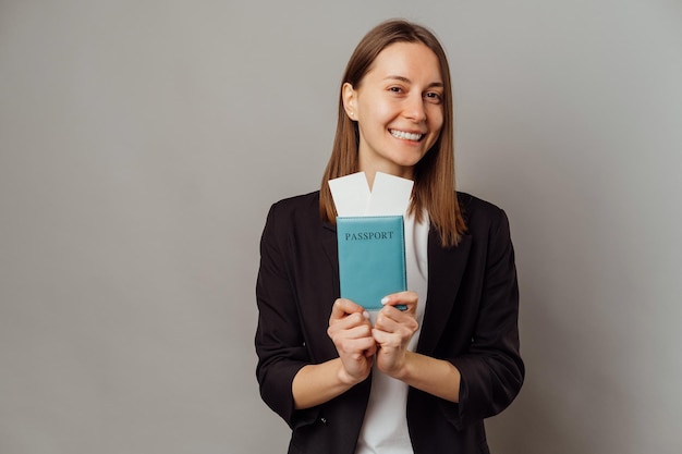 Une jeune femme charmante en casual montrant son passeport et ses billets de vacances.