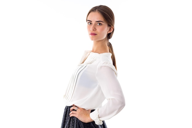 Jeune femme charmante debout en blouse blanche et jupe bkack sur fond blanc en studio