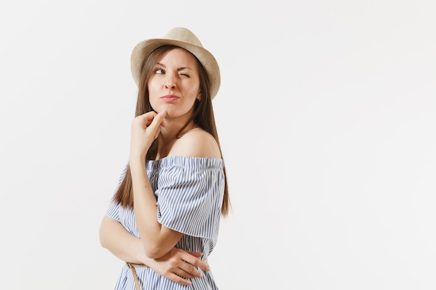 Jeune femme charmante élégante et tendre vêtue d'une robe bleue, chapeau mignon avec de longs cheveux bruns posant isolé sur fond blanc. Personnes, émotions sincères, concept de style de vie. Espace publicitaire. Espace de copie.