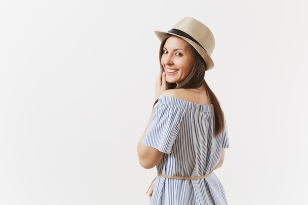 Jeune femme charmante élégante et tendre vêtue d'une robe bleue, chapeau mignon avec de longs cheveux bruns posant isolé sur fond blanc. Personnes, émotions sincères, concept de style de vie. Espace publicitaire. Espace de copie.