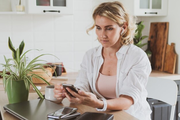 Une jeune femme charmante utilise un smartphone à la maison dans la cuisine