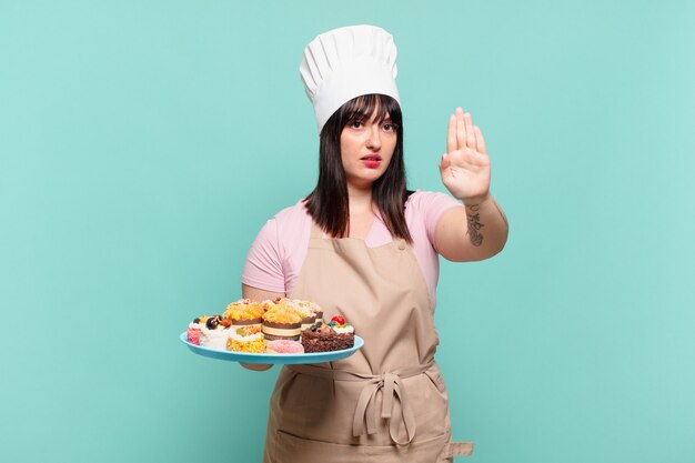 Jeune femme chef à l'air sérieuse, sévère, mécontente et en colère montrant la paume ouverte faisant un geste d'arrêt