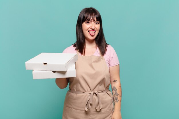 Jeune femme chef avec une attitude joyeuse, insouciante et rebelle, plaisantant et tirant la langue, s'amusant