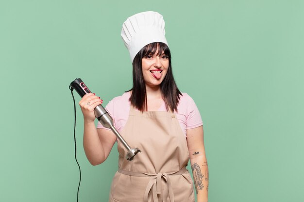 Jeune femme chef avec une attitude joyeuse, insouciante et rebelle, plaisantant et tirant la langue, s'amusant