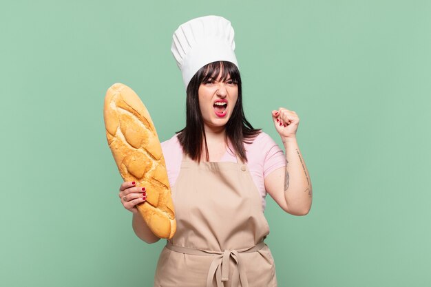 Jeune femme chef criant agressivement avec une expression de colère ou avec les poings serrés célébrant le succès