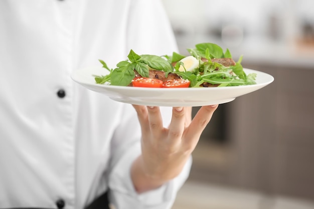 Jeune femme chef avec un plat savoureux en gros plan de cuisine