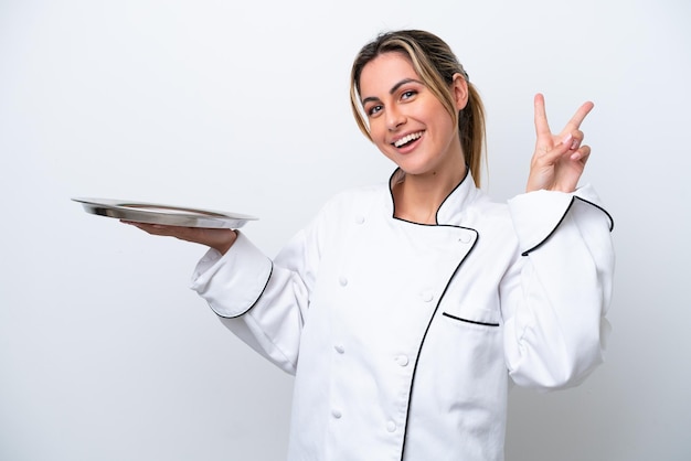 Jeune femme chef avec plateau isolé sur fond blanc souriant et montrant le signe de la victoire