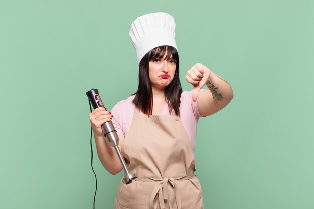 Jeune femme chef se sentant fâchée, en colère, agacée, déçue ou mécontente, montrant les pouces vers le bas avec un regard sérieux