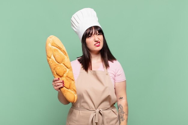 Jeune femme chef se sentant perplexe et confuse, avec une expression stupide et abasourdie en regardant quelque chose d'inattendu