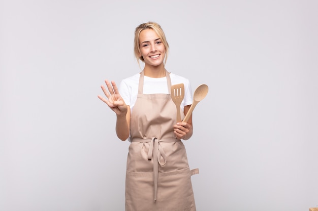 Jeune femme chef souriante et semblant amicale, montrant le numéro quatre ou quatrième avec la main vers l'avant, compte à rebours