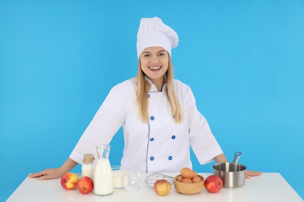 Jeune femme chef en uniforme sur fond bleu