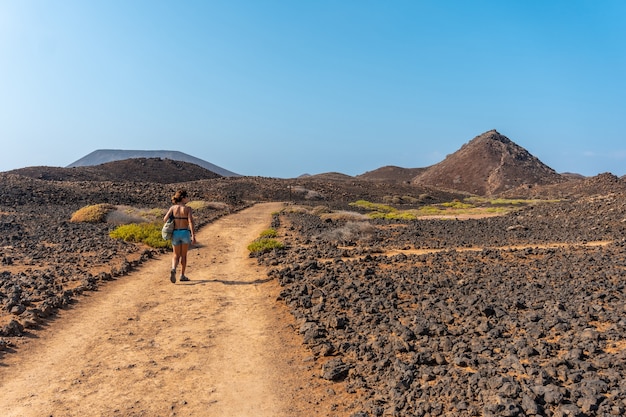 Une jeune femme sur le chemin au nord de l'Isla de Lobos, le long de la côte nord de l'île de Fuerteventura, Îles Canaries. Espagne