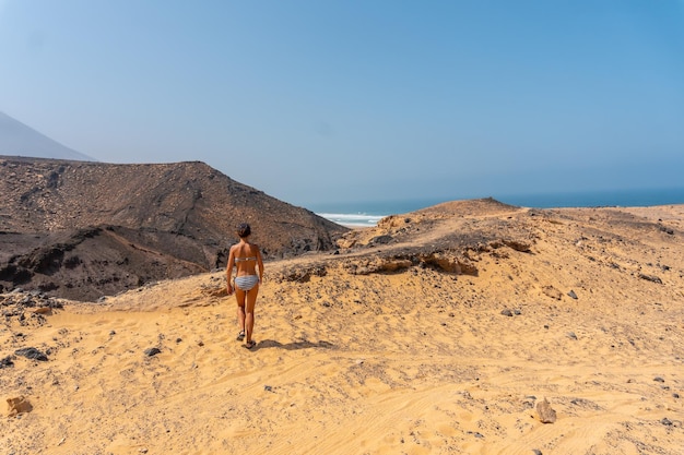 Une jeune femme sur un chemin de la plage sauvage Cofete du parc naturel de Jandia